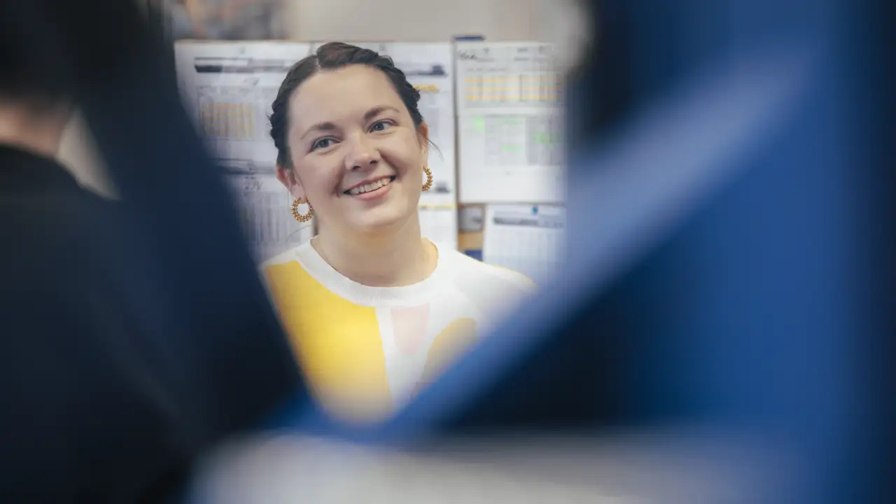 lächelnde Frau ist zu sehen - gelbe Ohrringe und gelbes Oberteil - nur kleiner Ausschnitt