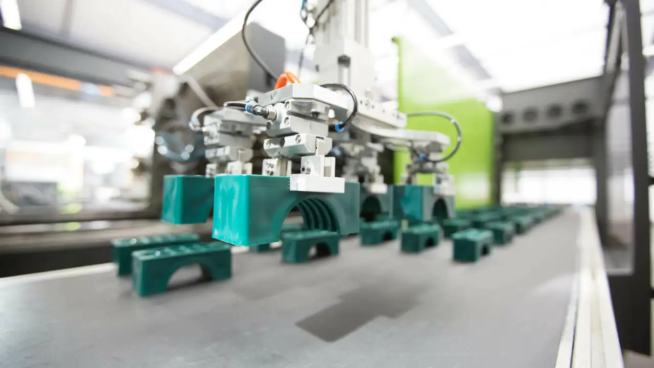 viele grüne kleine Teile auf einem Fließband, werden von Maschine bearbeitet - Herstellung von Teilen für Befestigungstechnik