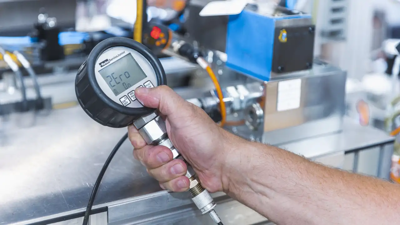 Hand hält Messmaschine vor Industriemaschine in der Hand